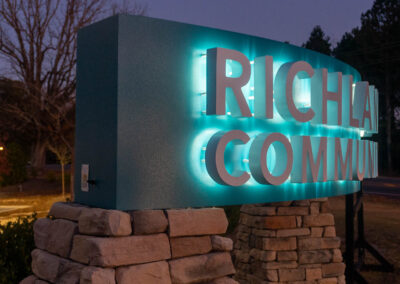 "An illuminated archway sign for Richland Creek Community Church with teal blue lighting and stone pillars set against a twilight sky."