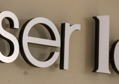 "Up-close view of 'Laser Lounge' 3D lettering with distinct shadows, showcasing the brand's sharp and precise image."