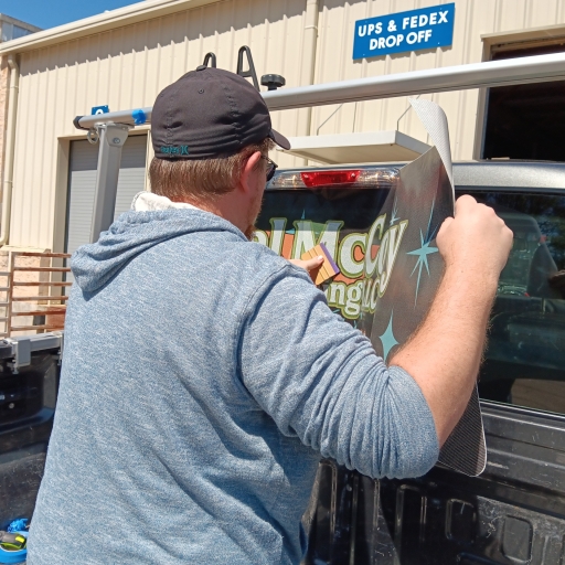 A SignCraft Solutions technician applying a vehicle wrap graphic to the rear window of a truck.