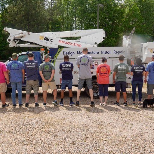 The SignCraft Solutions team gathered in front of their service equipment, showcasing a mix of casual and professional unity.