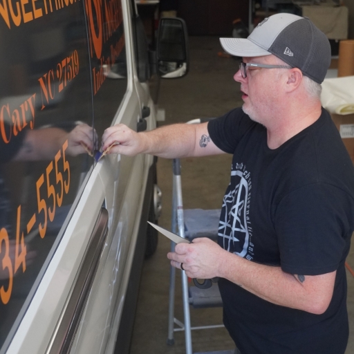 A SignCraft Solutions technician applying vehicle wrap to van
